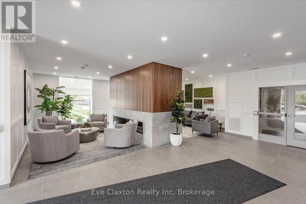 Building lobby with gray seating, a wooden fireplace feature, and potted plants. - 204 - 1880 Gordon Street E, Guelph