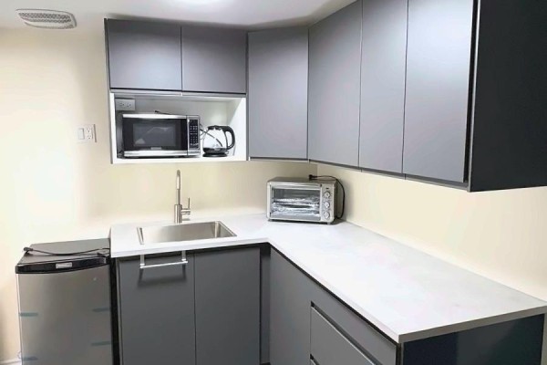 Kitchenette with grey cabinets, a sink, microwave, toaster oven, and a mini-fridge. - 204 - 198-200 Queen Street W, Toronto