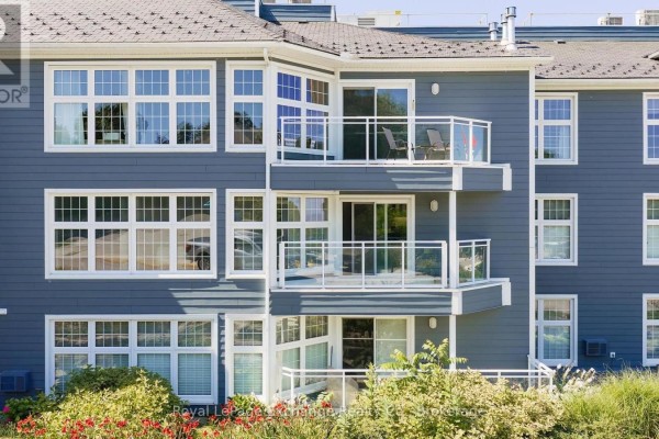 Close-up of the exterior of the apartment building showing stacked balconies with glass railings and white-framed windows. - 204 - 200 Harbour Street, Kincardine