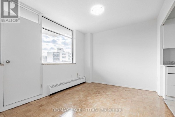 Small room with parquet flooring, large window, and white walls. - 204 - 2255 Weston Road, Toronto