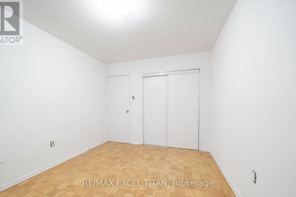 Bedroom with parquet flooring, white walls, and sliding closet doors. - 204 - 2255 Weston Road, Toronto