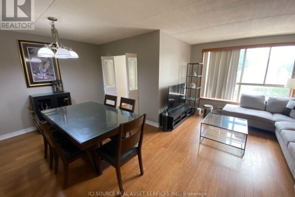 Living and dining area with a sectional sofa, glass coffee table, entertainment unit, and wood flooring. - 204 - 249 Major Mackenzie Drive E, Richmond Hill