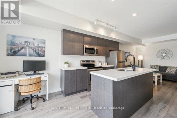 Open concept kitchen and living area with a large island and desk. - 204 - 3058 Sixth Line, Oakville