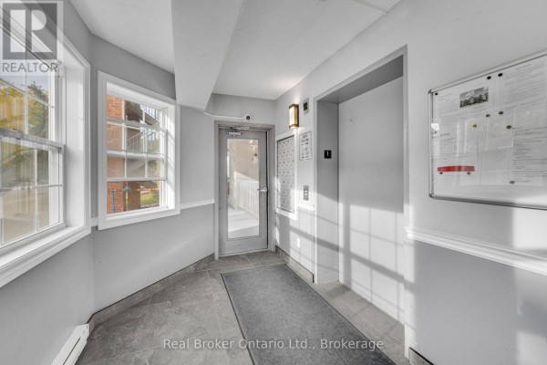 Interior hallway with light grey walls, tile floor, and elevator. - 204 - 4015 Kilmer Drive, Burlington