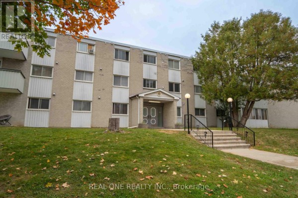 Apartment building exterior with grass and walkway. - 204 - 6 Walton Avenue, Kitchener