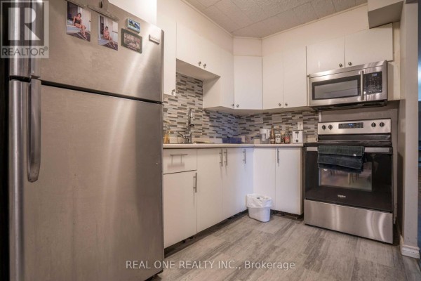 Kitchen with stainless steel refrigerator, microwave, stove, and white cabinets. - 204 - 6 Walton Avenue, Kitchener