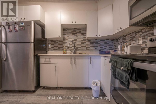 Corner kitchen view with stainless steel appliances and white cabinets. - 204 - 6 Walton Avenue, Kitchener