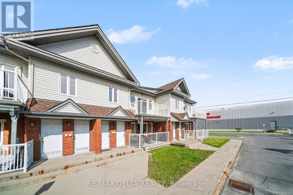 Side view of townhouse units with white siding and red brick, facing a large building. - 204 - 88 Lafleche Boulevard, Casselman