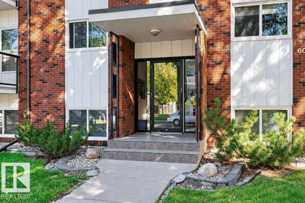 Close-up of the apartment building entrance with brickwork, glass doors, and steps. - #204 10540 80 Av Nw, Edmonton