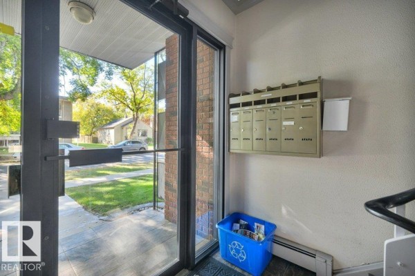 View inside the apartment building entrance showing mailboxes, a recycling bin, and a radiator. - #204 10540 80 Av Nw, Edmonton