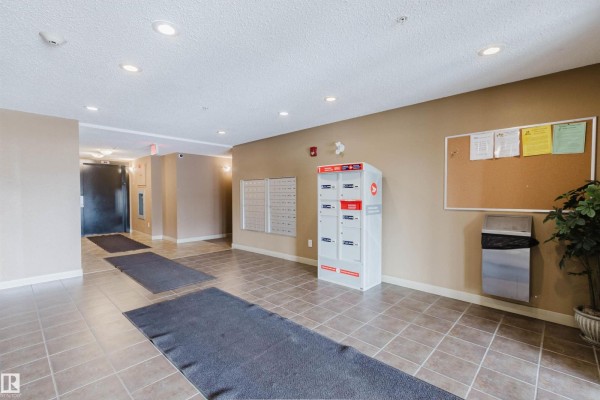 Interior building lobby with tile flooring, mailboxes, and a parcel locker. - #204 11803 22 Av Sw, Edmonton