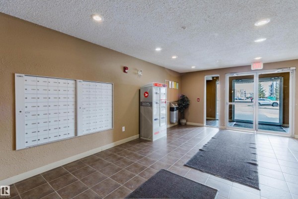 Building lobby with mailboxes, parcel locker, trash can, and glass entrance doors. - #204 11803 22 Av Sw, Edmonton