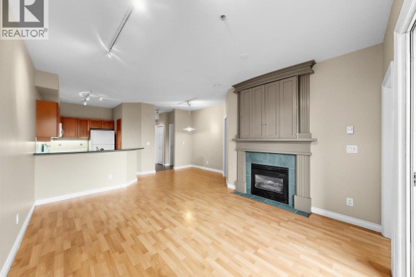 Living room and kitchen area with hardwood floors, fireplace, and breakfast bar. - 204 131 W 3rd Street, North Vancouver