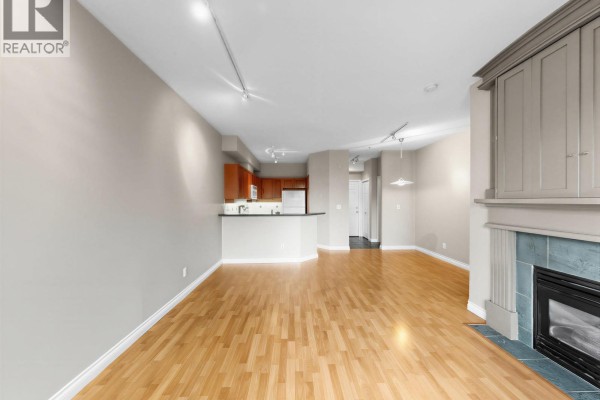 Living room showing the open layout, hardwood floors, and view into the kitchen. - 204 131 W 3rd Street, North Vancouver