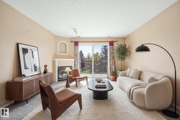 Open concept living area with kitchen, sofa, and balcony access. - #204 16303 95 St Nw, Edmonton