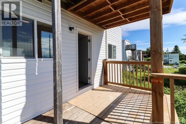 Wooden deck with railing and an open doorway leading inside a residential unit. - 204-206 St. James W Street, Saint John