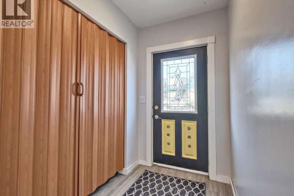Interior view of a home entry with a dark door and wood-paneled closet. - 204 2nd Avenue W, Biggar