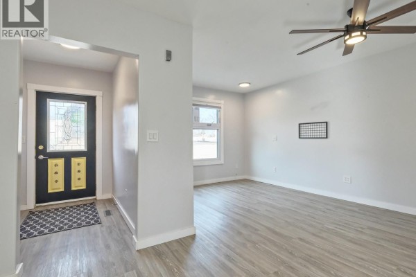 View of an entry and living room with light grey walls and wood-look flooring. - 204 2nd Avenue W, Biggar