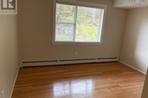 Living room with hardwood floors, large window, and a door to outside. - 204 41 Moirs Mill Road, Bedford