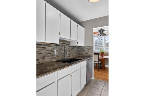 View of kitchen counters, white cabinets, backsplash, and sink area with a dining table visible beyond. - #204 7407 171 St Nw, Edmonton