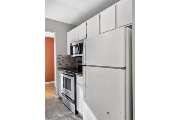 Kitchen with white cabinets, stainless steel appliances including a refrigerator and oven, and a tiled floor. - #204 7407 171 St Nw, Edmonton
