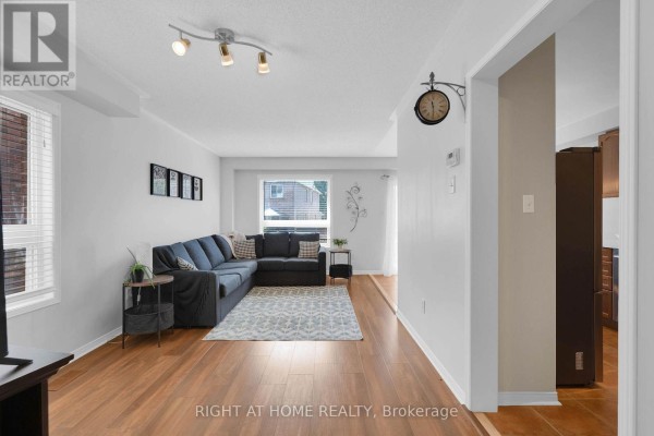 Living room with a sectional sofa, rug, and wood laminate flooring. - 204 Burgess Crescent, Newmarket