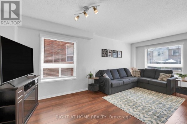 Living room with a large television, sectional sofa, and windows. - 204 Burgess Crescent, Newmarket
