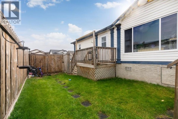 Side yard of a mobile home with a wooden fence and a deck. - 204 Elm Street, Fort Mcmurray