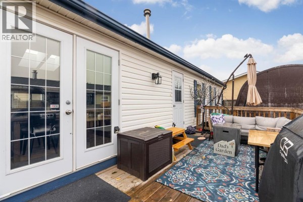 Wooden deck with patio furniture, a grill, and French doors leading outside. - 204 Elm Street, Fort Mcmurray