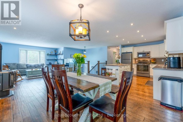 Open concept living room & kitchen with dining table, stove, sofa, and island - 204 Golf Course Road Wasaga Beach