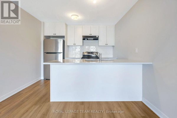 Modern kitchen with white cabinetry, stainless steel appliances, and a breakfast bar. - 204 Lillian Freiman Private, Ottawa