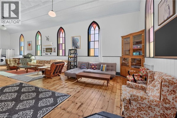 Spacious living area featuring colorful arched windows, wooden floors, and various seating arrangements. - 2040 Main Street, Walsingham
