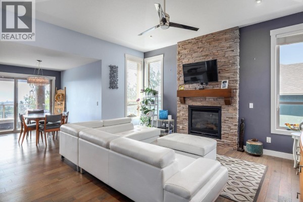 Living room with a large white sectional sofa and stone fireplace. - 2040 Rosealee Lane Unit# 35, West Kelowna