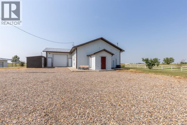 White roll-up garage door and two adjacent doorways on a white metal building facade. - 204004 Twp Rd 6-4, Raymond