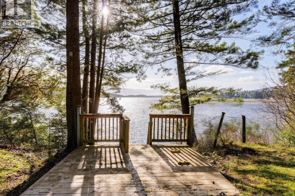 Stairs leading down to the water's edge, with sandy beach visible. - 2042 Glenidle Rd, Sooke