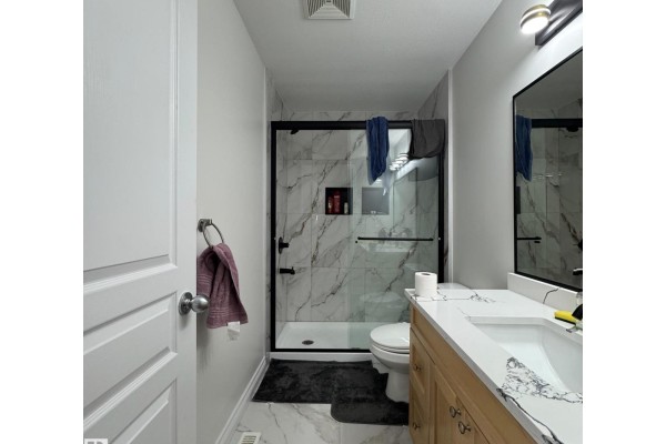 A smaller bathroom with a pedestal sink, toilet, and a corner shower with frosted glass doors. - 2043 49a Nw, Edmonton