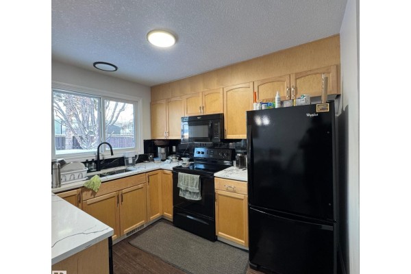 Brown reclining sofas and a coffee table in a living room with dark wood floors and a modern fireplace. - 2043 49a Nw, Edmonton