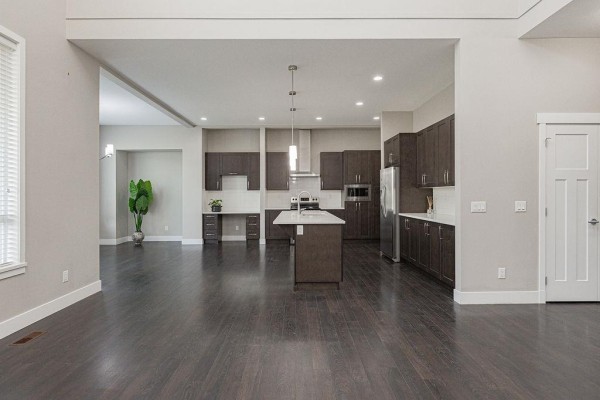 View of the open-concept kitchen with dark wood cabinets and island from the living area. - 20443 83a Avenue, Langley