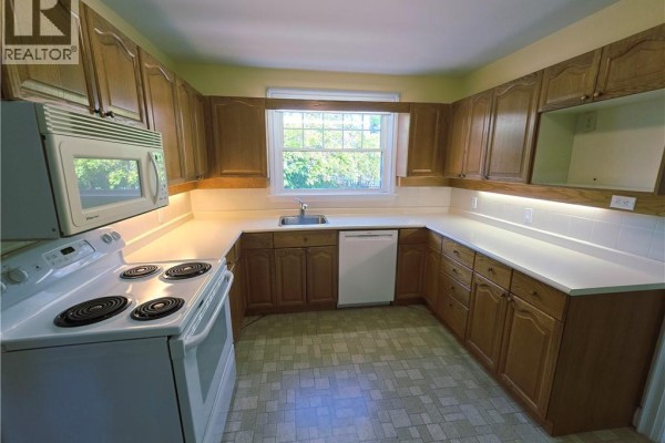 U-shaped kitchen with light wood cabinets, white appliances, white countertops, and a checkered floor. - 2047 James Street, Burlington