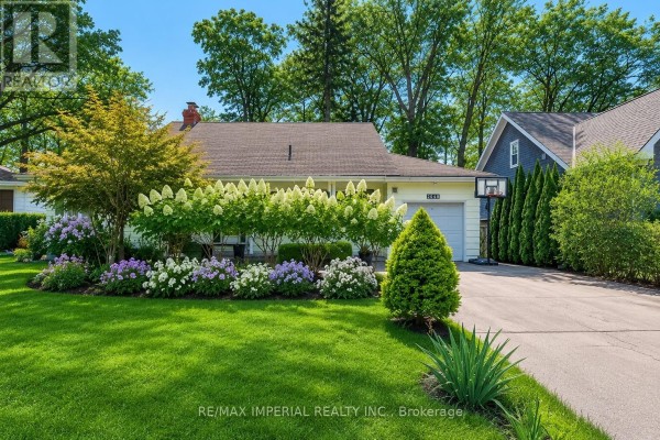 Front view of a single-story house with a white garage door and a basketball hoop. - 2048 Devon Road, Oakville
