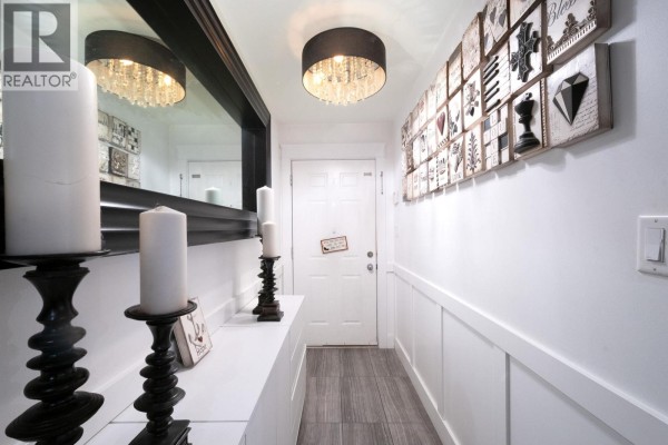 Interior hallway with white walls, wood-look tile floor, and decorative wall art. - 2048 Triumph Street, Vancouver