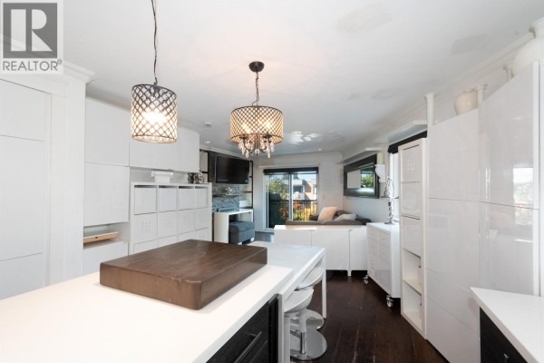 Modern white kitchen with an island, dark wood floors, and open concept living space. - 2048 Triumph Street, Vancouver