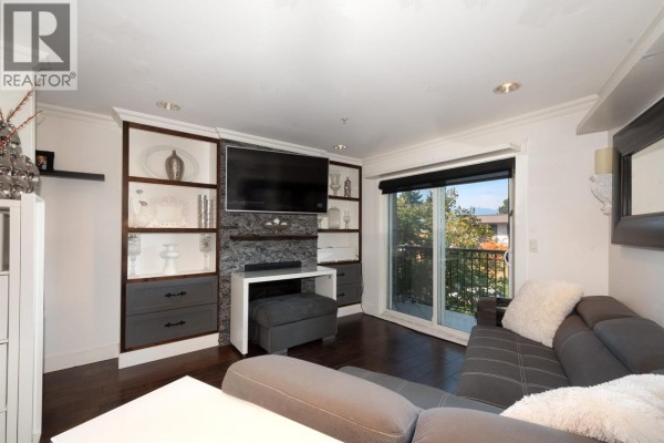 Living room with dark wood floors, grey sectional sofa, and built-in shelving. - 2048 Triumph Street, Vancouver