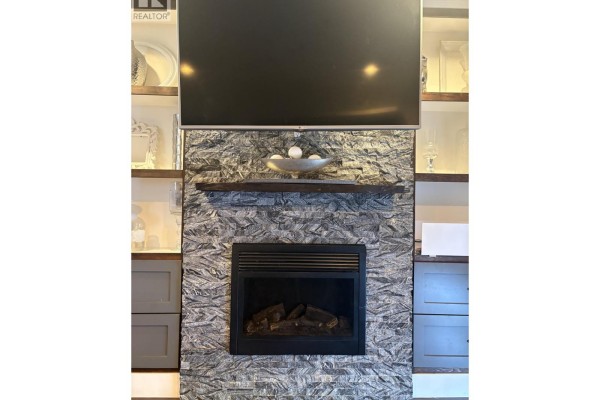 Close-up of a gas fireplace with grey tile surround and built-in shelving. - 2048 Triumph Street, Vancouver