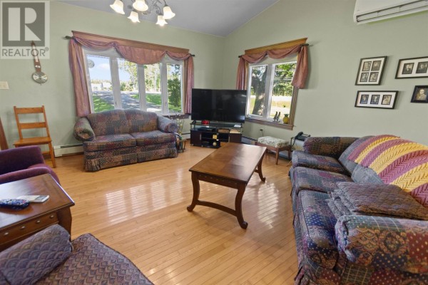 Living and dining room with hardwood floors, couches, a dining table, and kitchen access. - 2049 Georgetown Road, Cardigan