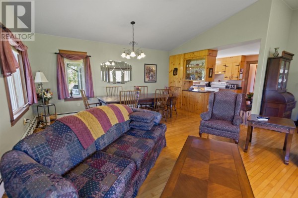 Living and dining room with hardwood floors, couches, a dining table, and mirrored wall decor. - 2049 Georgetown Road, Cardigan