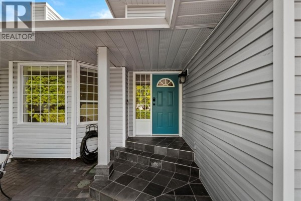 Entrance to the house showing the teal front door, tiled steps, bay window, and grey vinyl siding. - 2049 Tremerton Drive, Kamloops