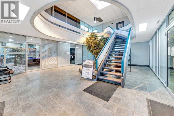 Lobby view of the staircase, central planter, and offices with glass doors. - 205, 5009 48 Street, Lloydminster