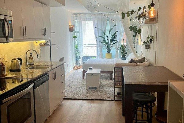 Studio apartment interior showing a compact kitchen, dining area, and living space with a bed. - 205 - 10 Willison Square, Toronto