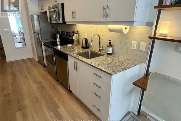 Detailed view of a kitchen counter with granite, sink, stainless steel appliances, and cabinets. - 205 - 10 Willison Square, Toronto